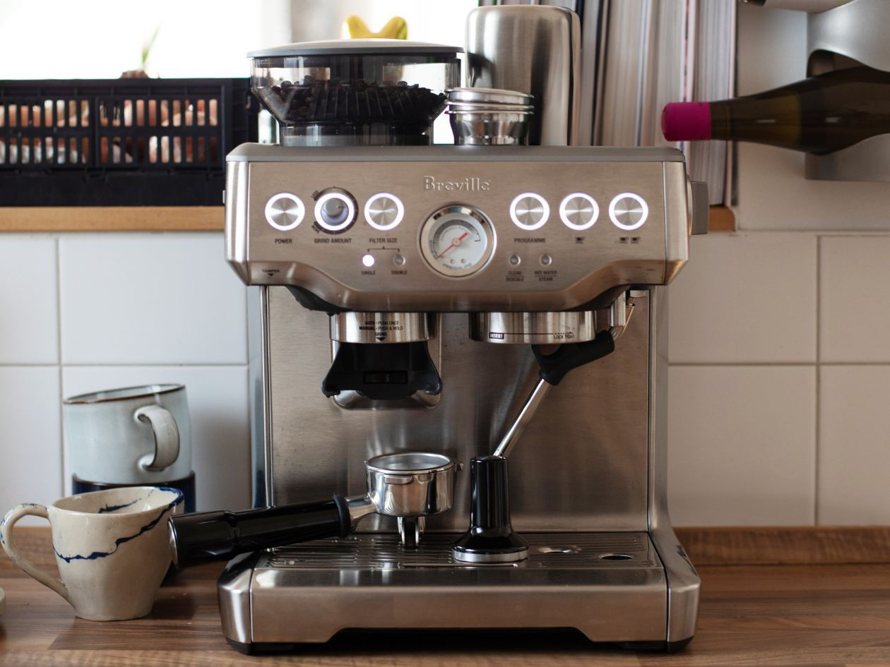 Stainless steel espresso machine on a kitchen counter with cups beside it